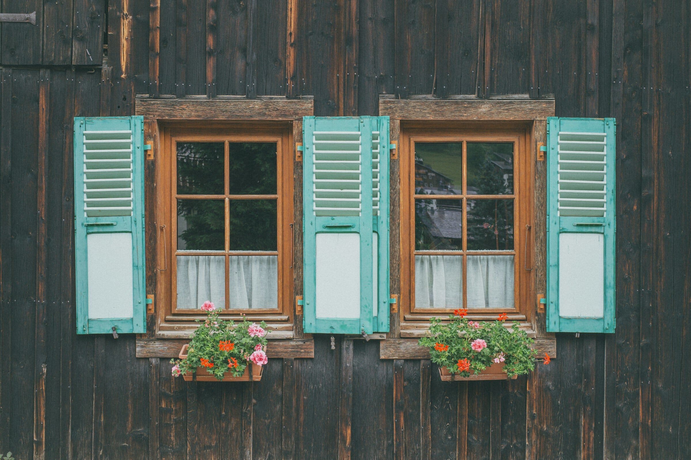 Volets persiennés turquoise sur une façade de chalet en bois